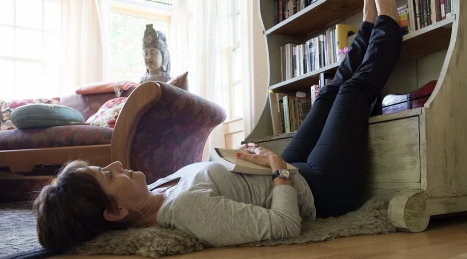 Sarah laying down with book and feet resting on bookcase